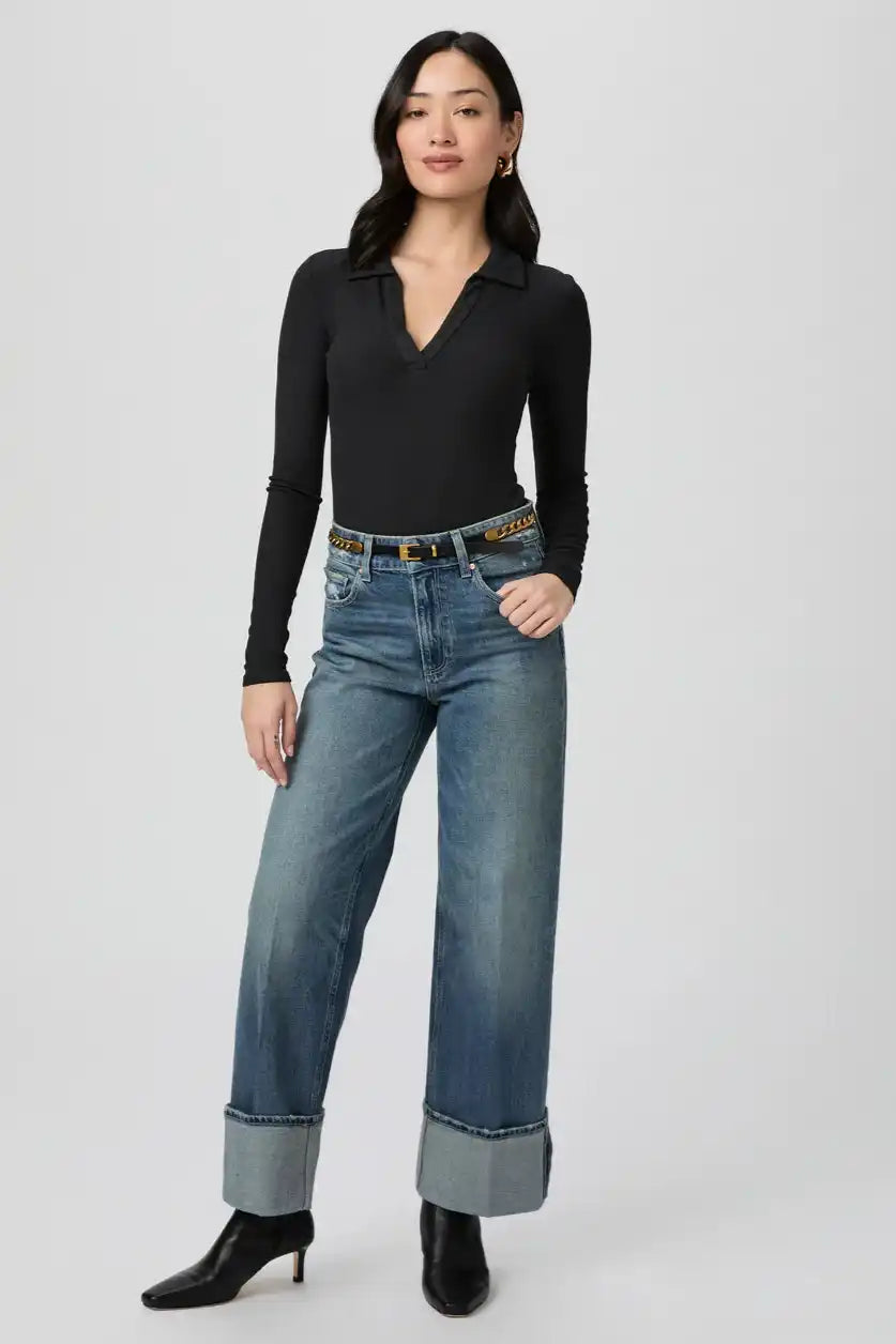 Wide-leg blue jeans with large folded cuffs paired with a black v-neck top.